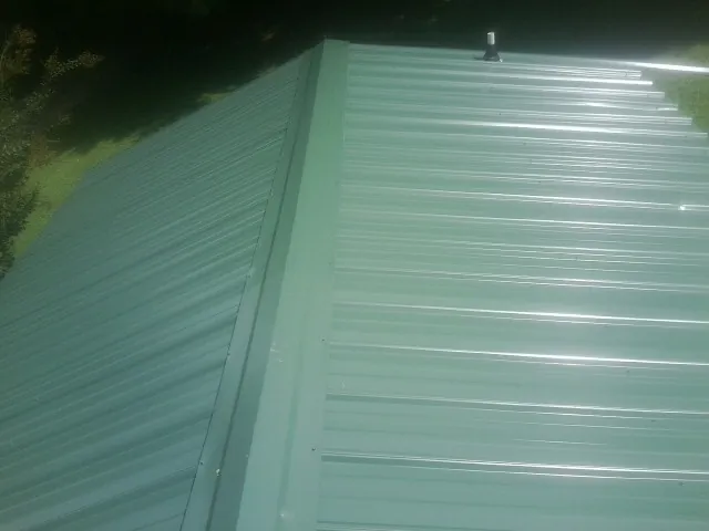 New green metal panels meeting at the ridge of a roof — Flat Roof Repair work by our crew in Abbottstown