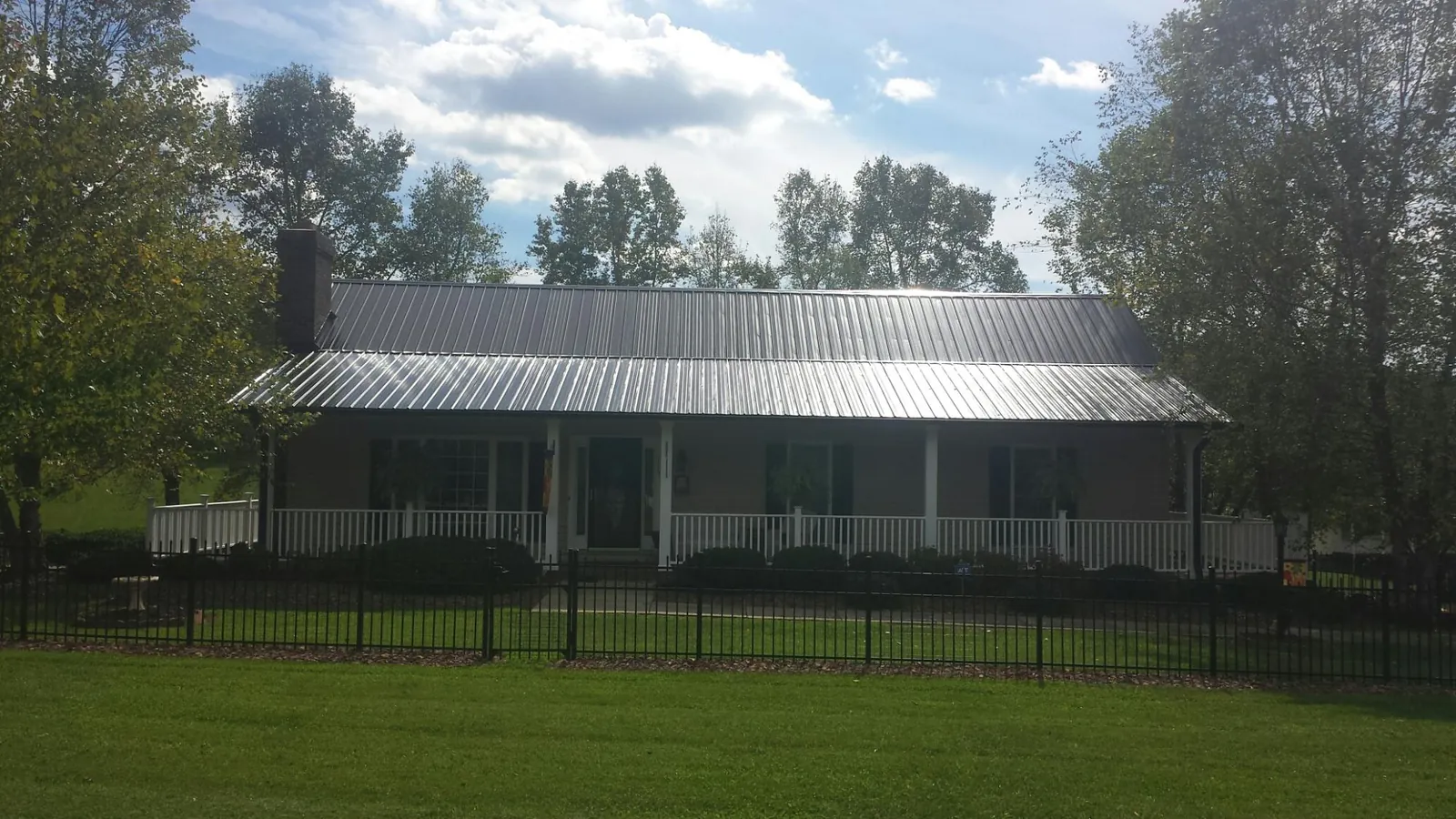 Gray metal roof on a brick ranch with a full width front porch — Gutter Guard Installation work by our crew in Abbottstown