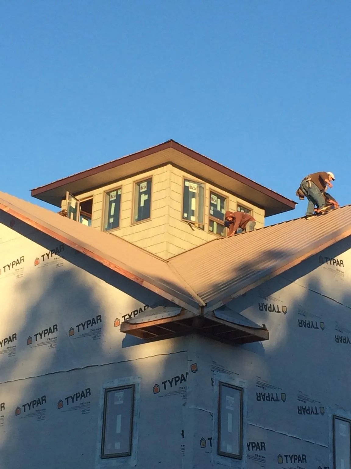 Roofers working around a rooftop cupola on a new metal roof at sunset — Roof Waterproofing in Abbottstown by Roofing Brothers